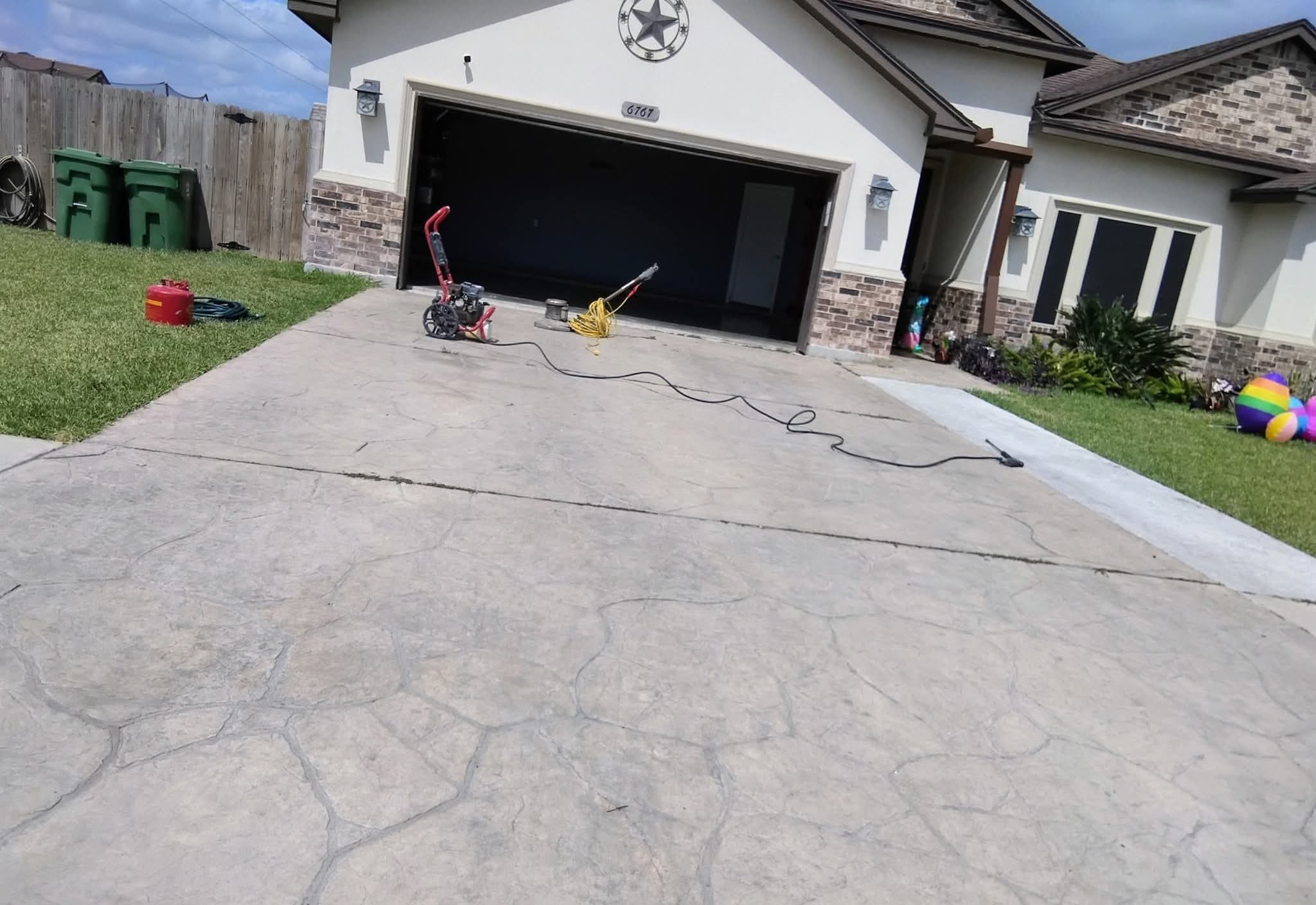 Grey stamped concrete driveway before treatment, weathered and unsealed.