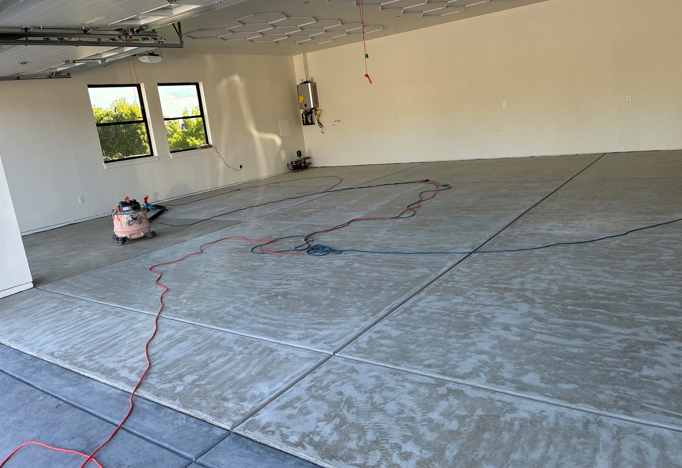 Bare concrete slab of a large garage after grinding, before any coating is applied.
