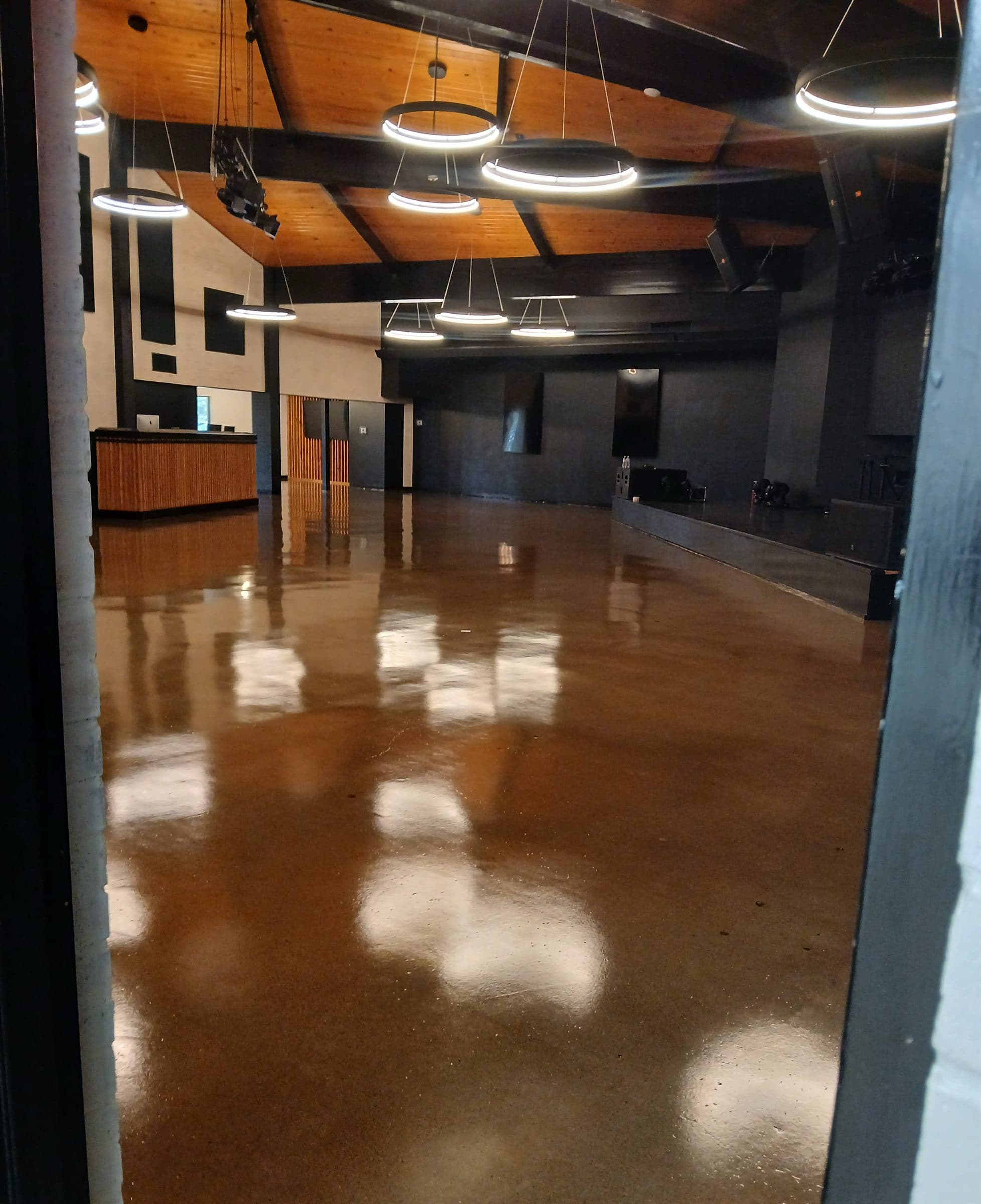 Warm brown polished concrete floor reflecting ring lights across an open event space.