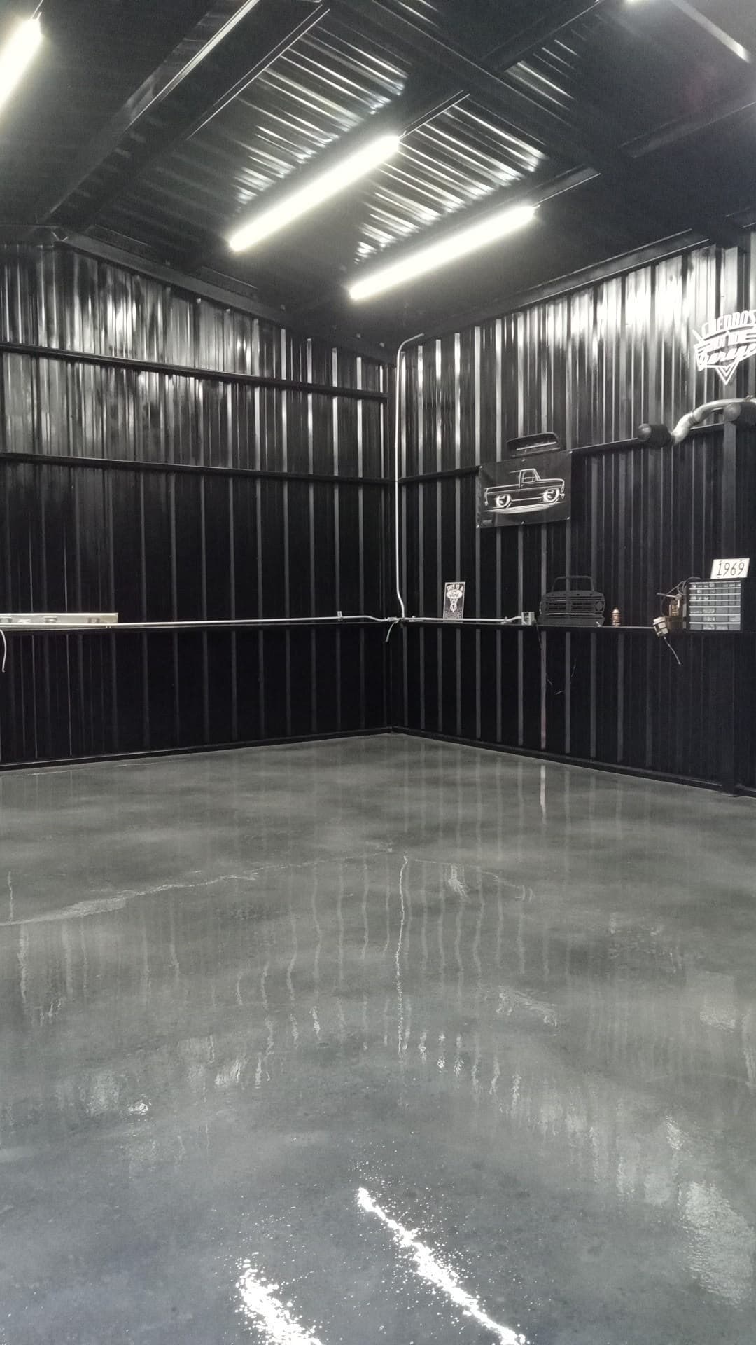 Grey coated concrete floor inside a metal workshop building.