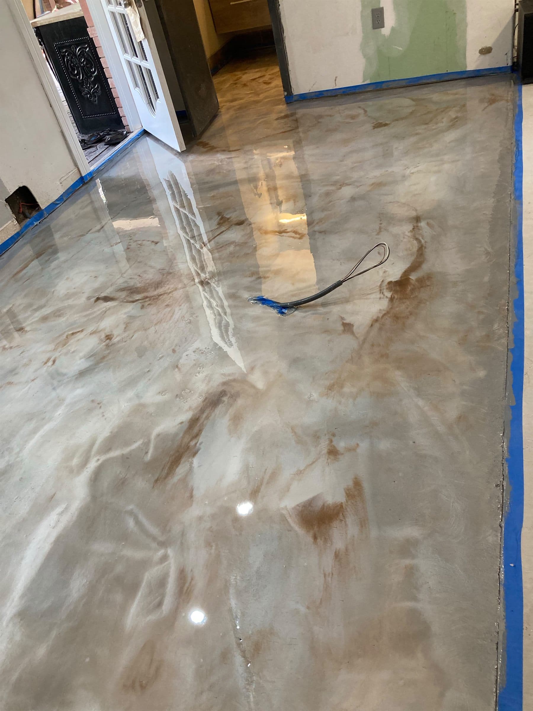Pearl and bronze metallic epoxy floor with hand-worked veining, poured wall to wall in an interior room.
