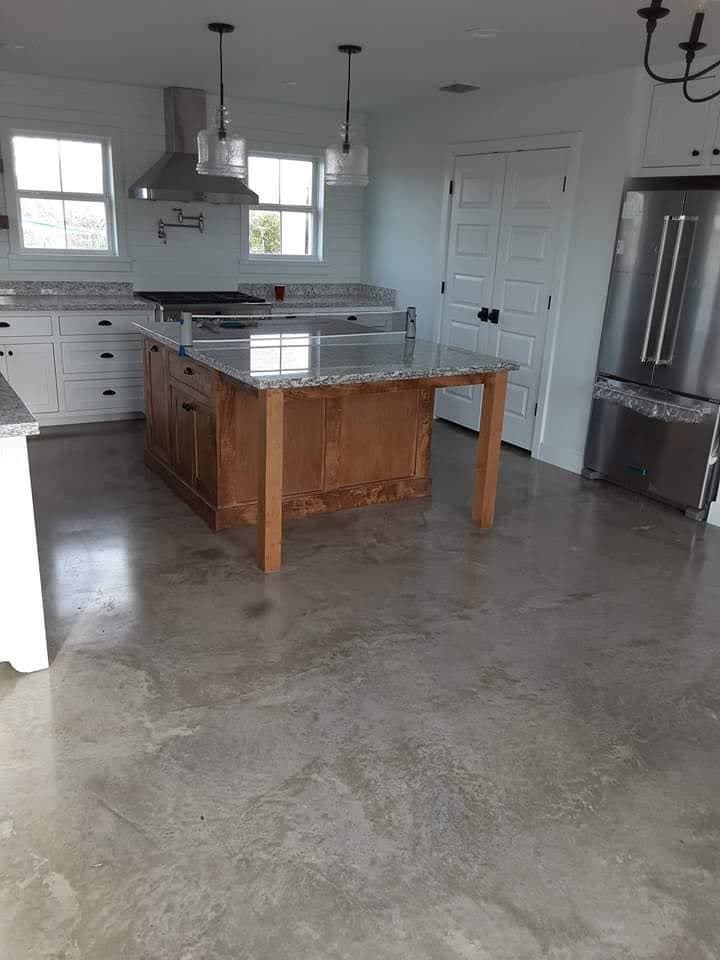 Smooth grey concrete floor in a finished kitchen, reflecting the light from the windows.