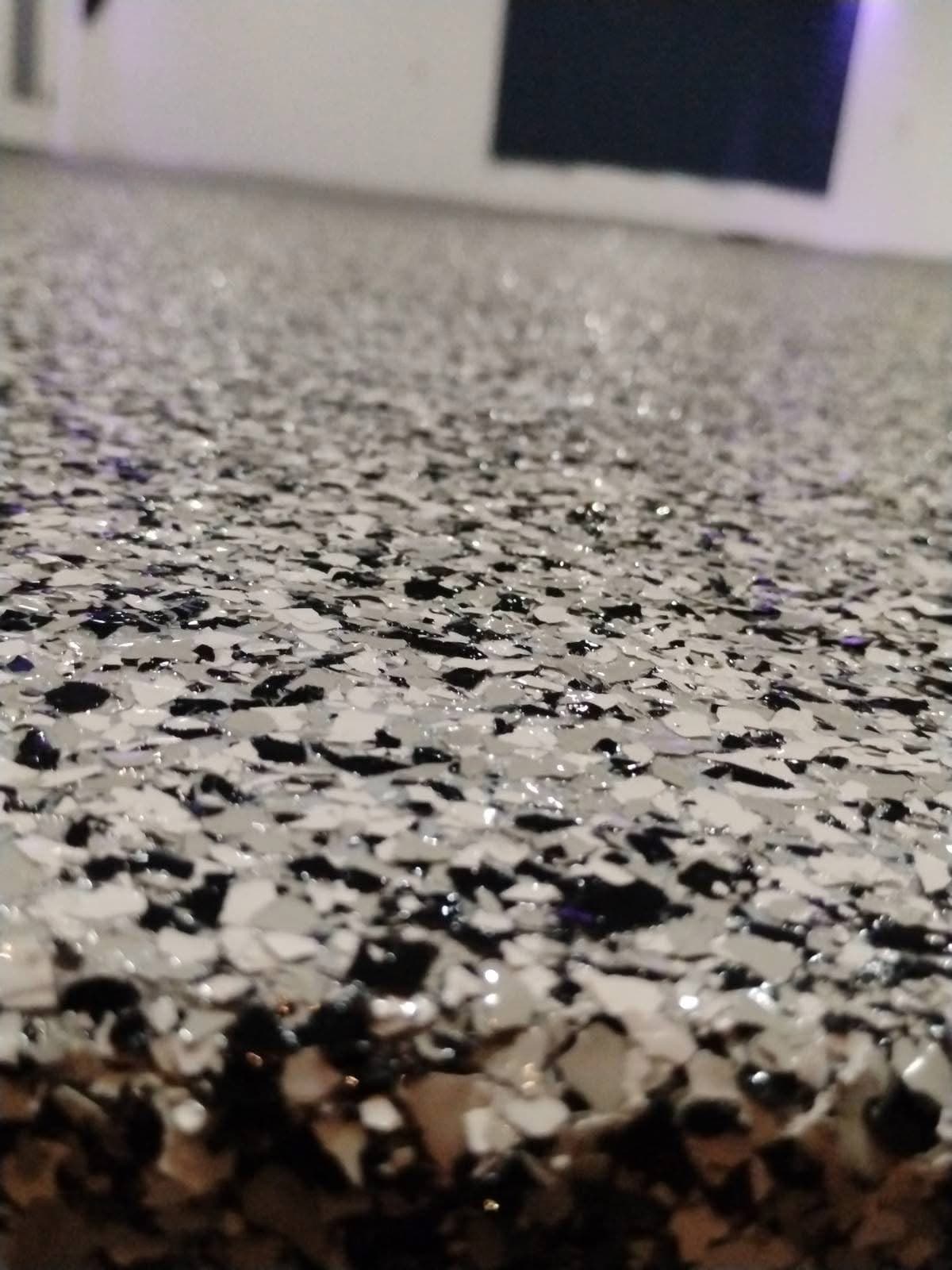 Close view of a black, white and grey vinyl flake floor sealed under a clear topcoat.