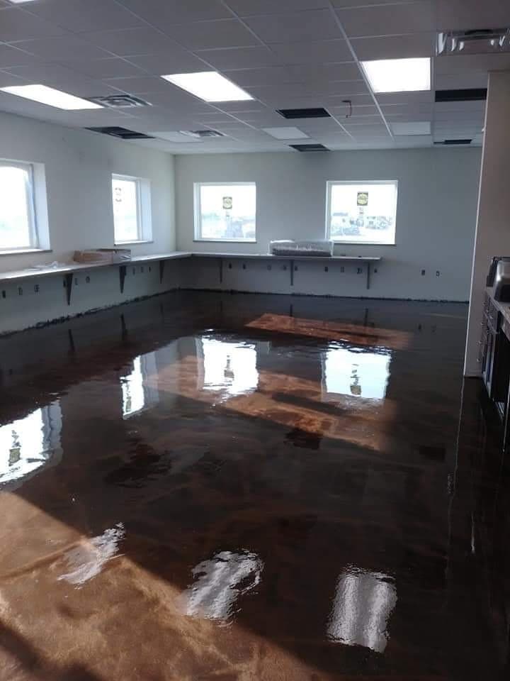 Dark copper metallic epoxy floor reflecting the windows of a finished office interior.